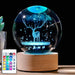 Luminous crystal ball with LED lights, featuring a deer and stars, on a wooden base with a multicolor remote control.